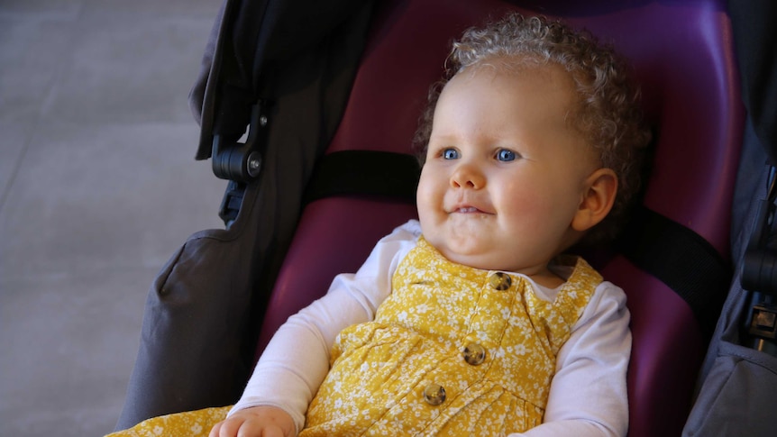 14 month old Wynter Clarkson looks cheerful in her stroller despite her rare disease.