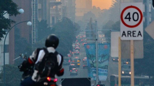 Smoke chokes Perth's CBD as traffic filters down St George's Terrace at sunrise