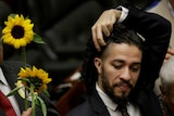 Congressman-elect Jean Wyllys gestures near a man holding sunflowers.