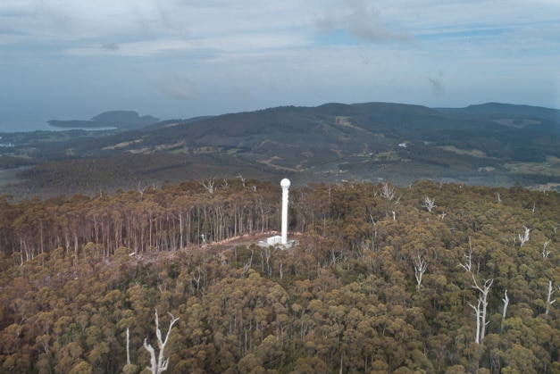 Weather radar mast pictured amongst bushland on a hill.