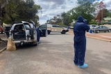A forensic police officer in a boiler suit photographs a crime scene in Boulder, Western Australia.