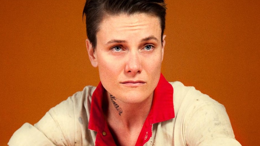 Female model Casey Legler poses for a photo, wearing work overalls.