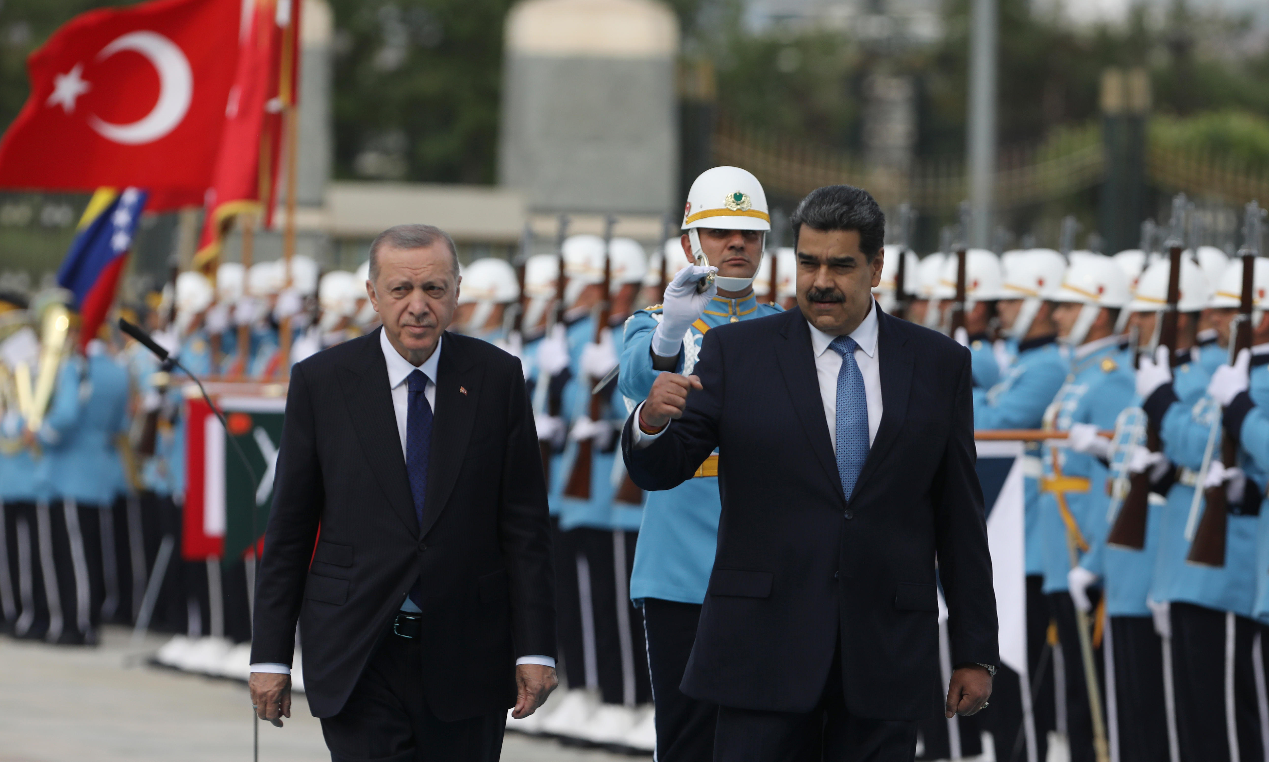 Recep Tayyip Erdogan and Nicolas Maduro in dark suits walking next to a military honour guard in light blue clothing