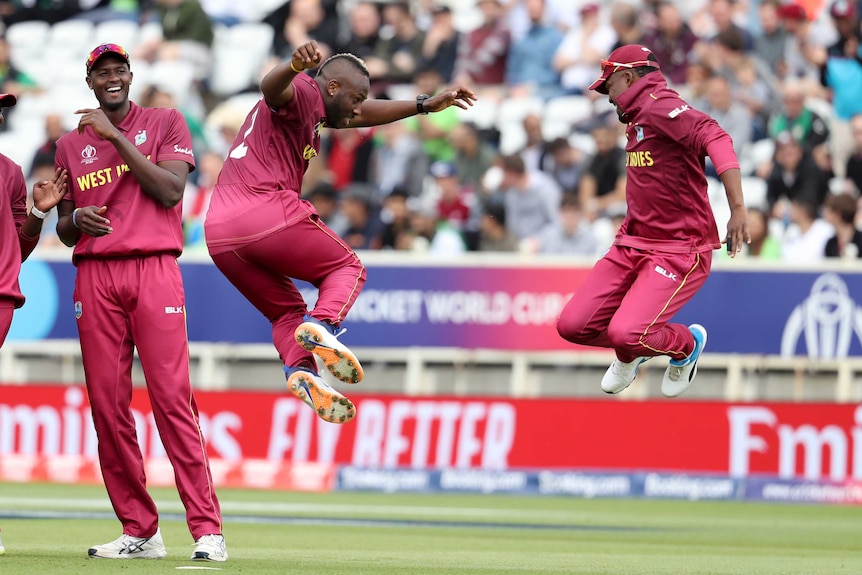 Two West Indies cricketers leap in the air to celebrate a wicket in a World Cup match.