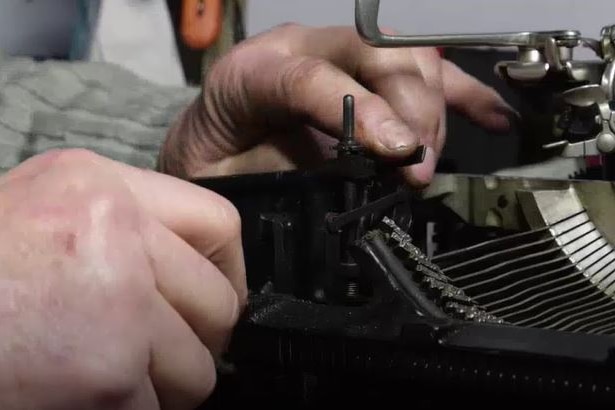 Hands fixing up a typewriter.