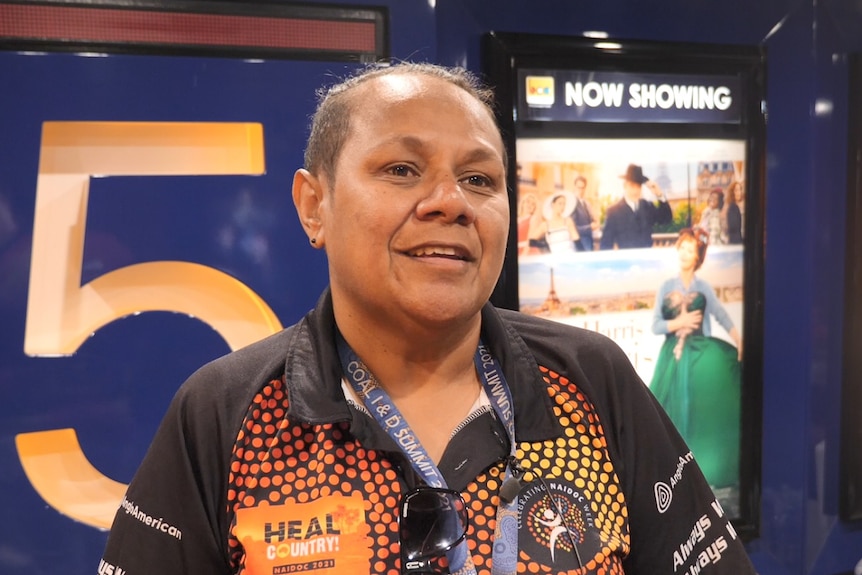 Barada woman Nicky Muller smiles at the camera while standing outside a movie theatre