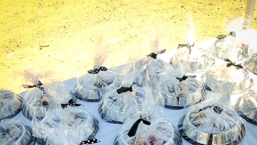 Dog bowls filled with treats and wrapped in cellophane lined up on a table.
