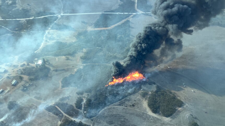 An aerial photo of a small bushfire burning in bushland, showing flames and smoke.