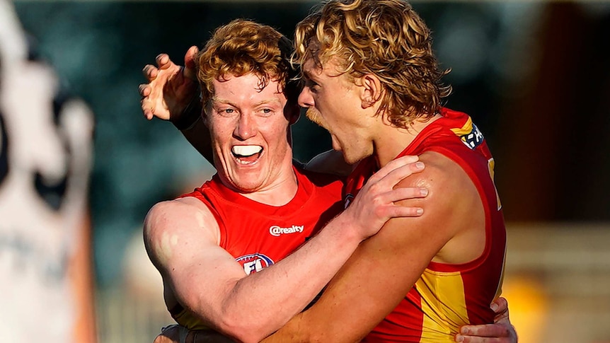 two Gold Coast Suns players hug in celebration