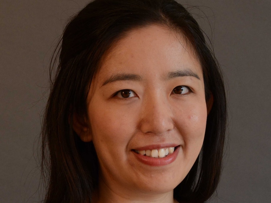 A headshot of an Asian woman with black hair smiling at the camera.