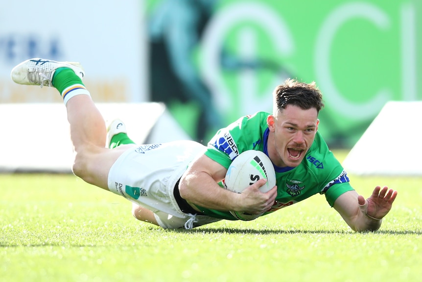 A Canberra Raiders NRL player dives on the ground to score a try.