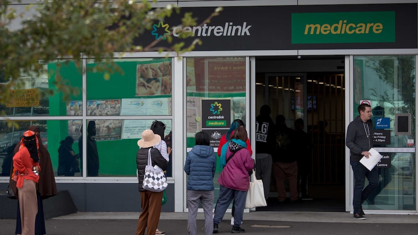 People wait on footpath outside Centrelink.