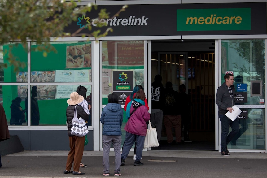 People wait on footpath outside Centrelink.