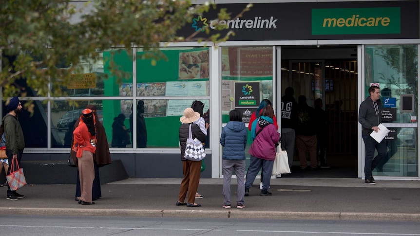 People wait on footpath outside Centrelink.