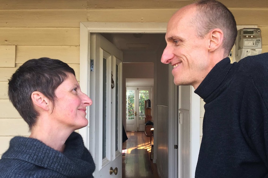 Rachael and Andy looking lovingly into each other's eyes outside their home.