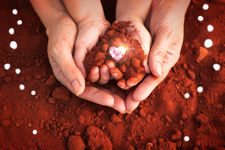 An image of a child and adult's hands holding red dirt with a superimposed picture of a pink, heart-shaped diamond.