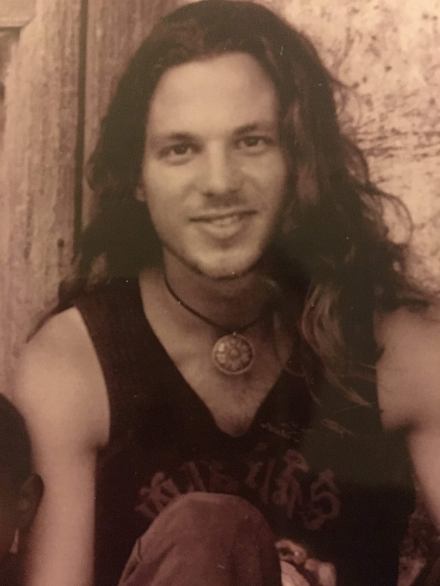 An old picture of Brett Sutton, where he has long hair and is wearing a singlet