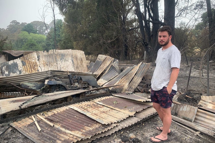 A man stands next to his burnt out home.