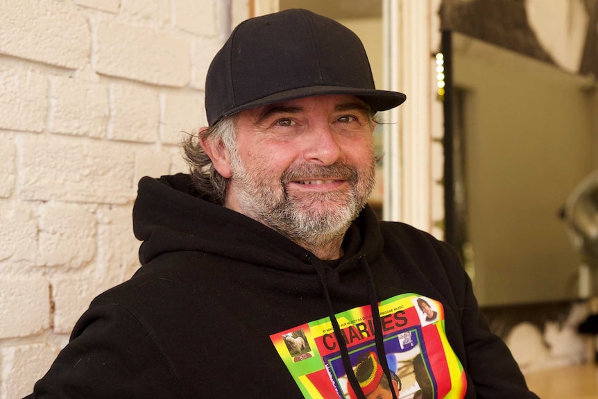 A portrait of Frank Valvo, a man with a white beard wearing a black baseball cap and hoodie.