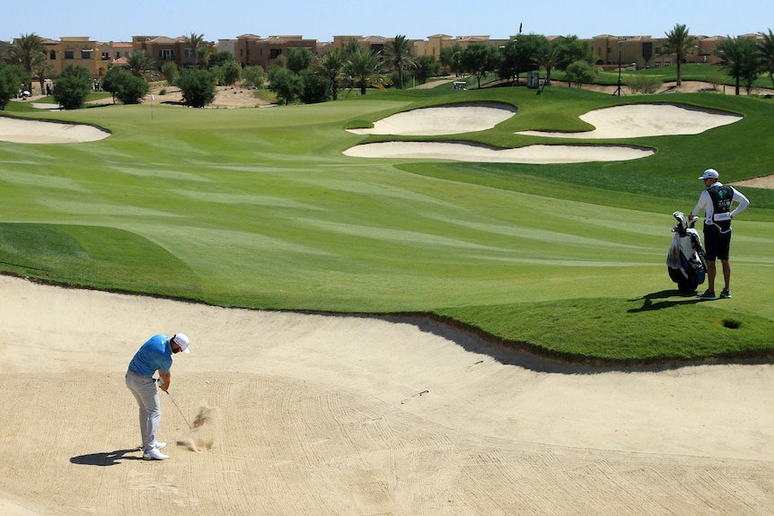 Dustin Johnson plays a shot out of a fairway bunker