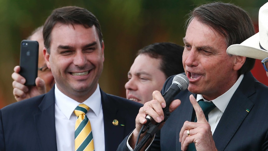 Flavio Bolsonaro stands smiling broadly with his father Brazilian President Jair Bolsonaro.