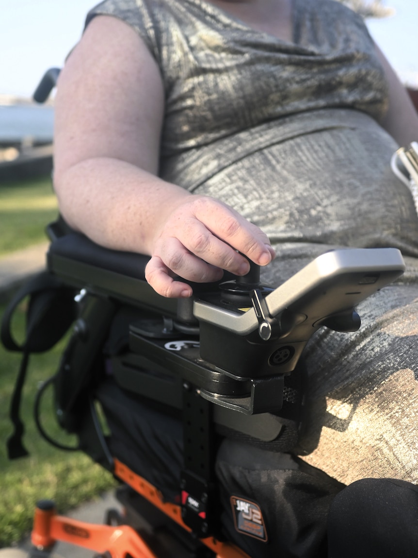 Close up of a woman's hand, directing an electric wheelchair.