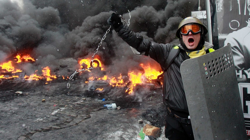 A pro-European protester swings a metal chain during clashes with riot policemen