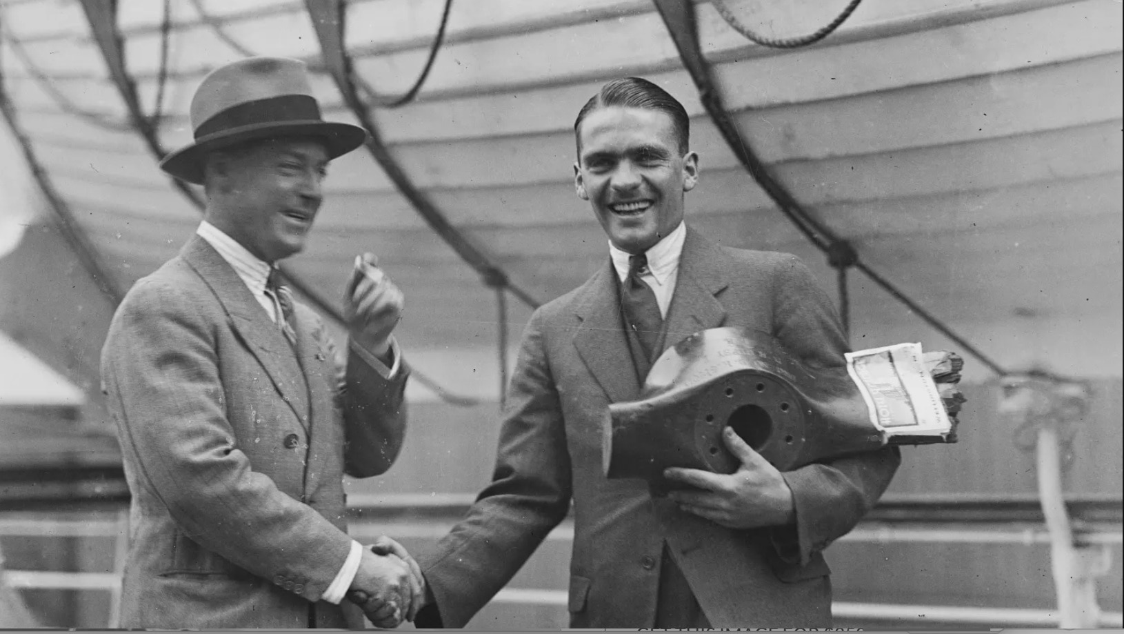 Un hombre sonriente con traje le da la mano a otro hombre.