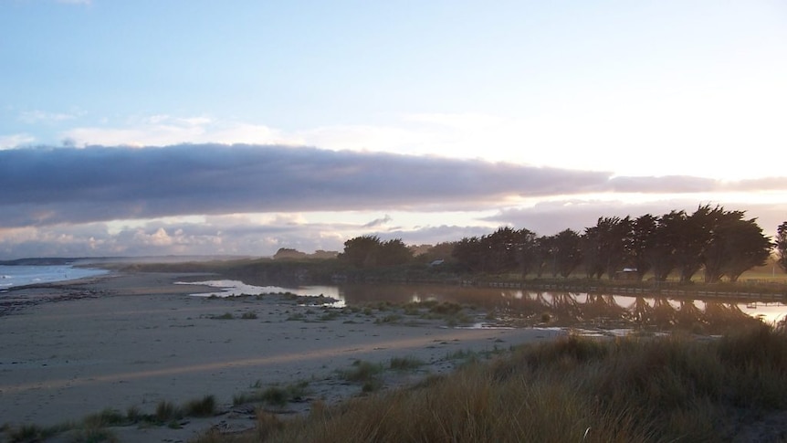 A river with a small ridge of sand between the river and the ocean.