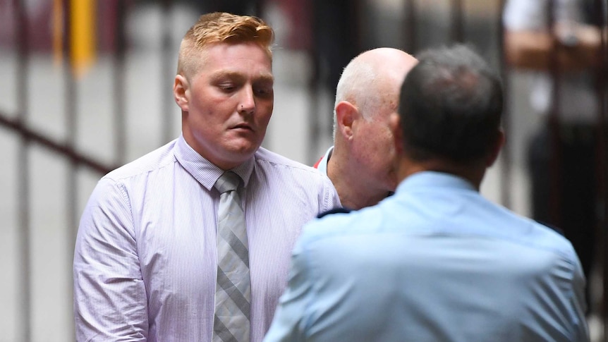 Travis Wills, a young man with light blonde hair, is escorted into court.