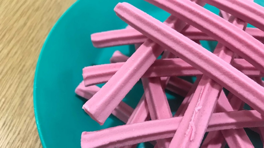 Pink musk sticks arranged on a green plate
