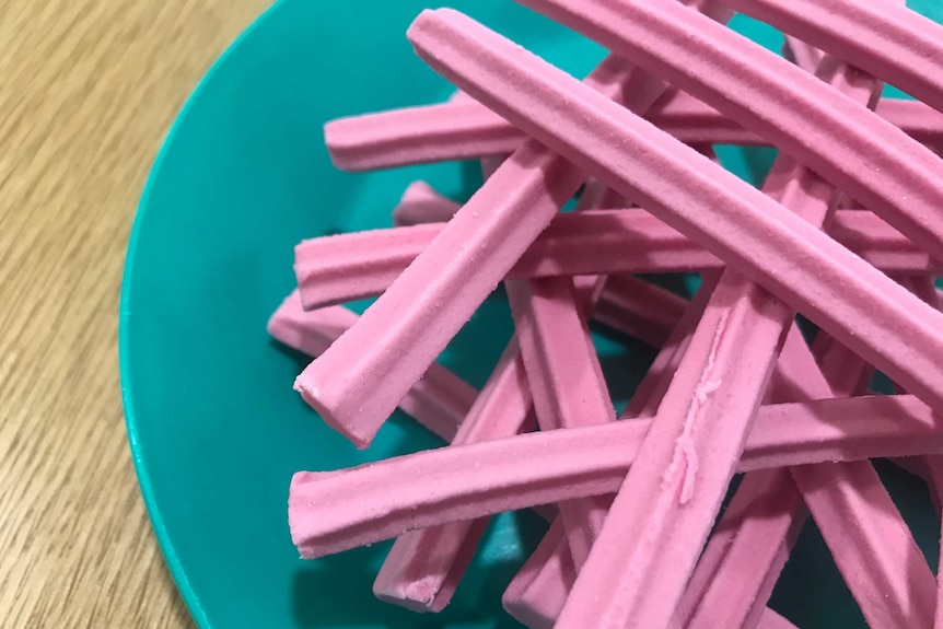 Pink musk sticks arranged on a green plate