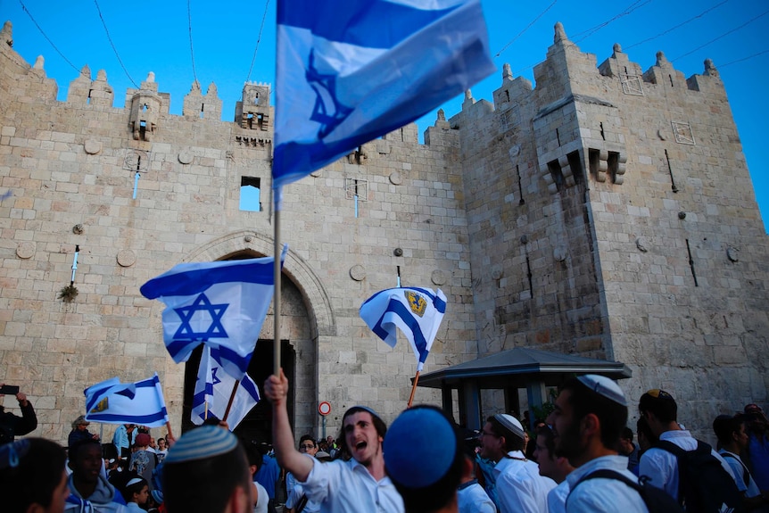 Israelis wave national flags outside the Old City's Damascus Gate.