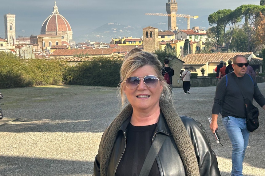 A lady taking a photo with an Italian city behind her