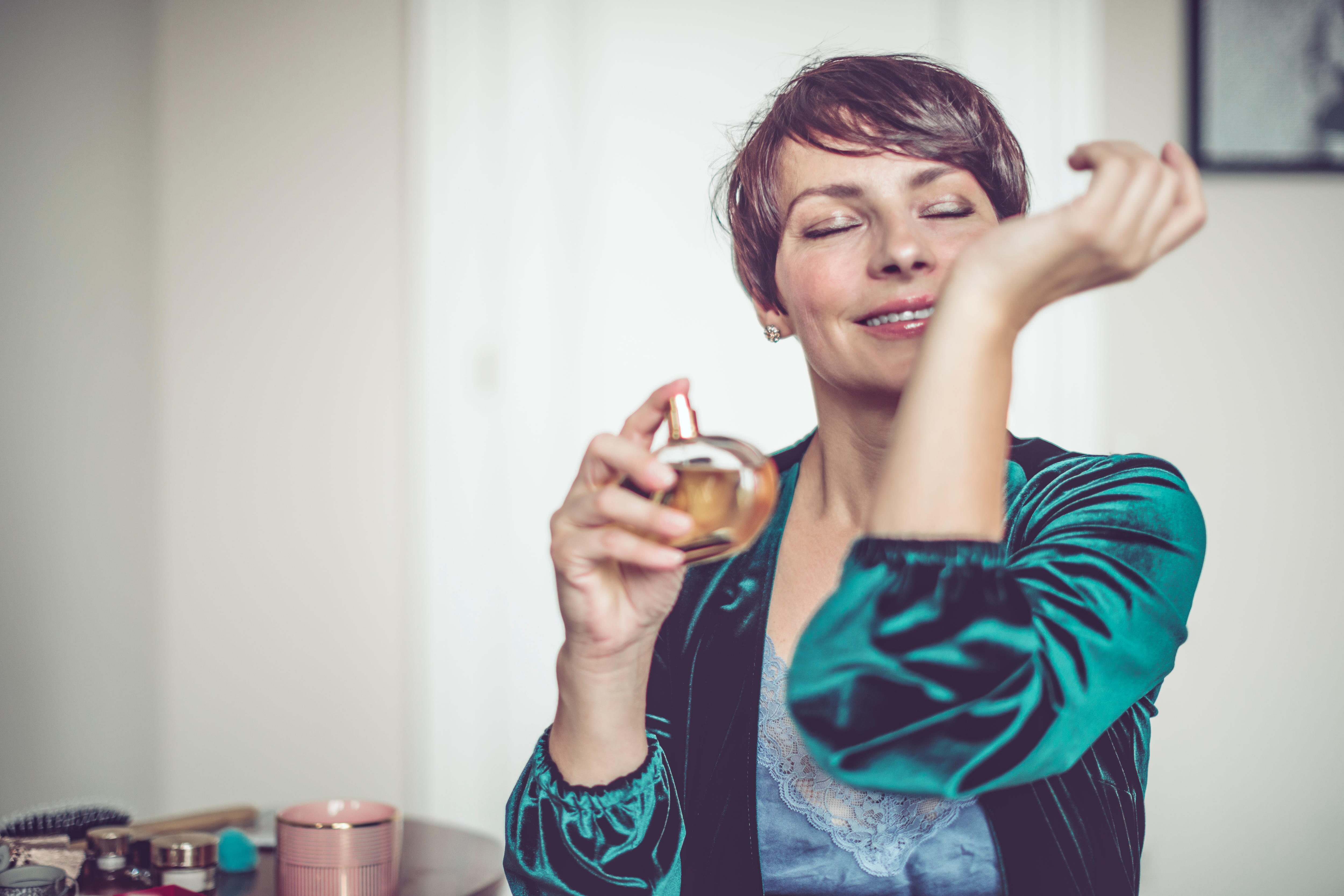 Woman spraying perfume on herself and smelling wrist