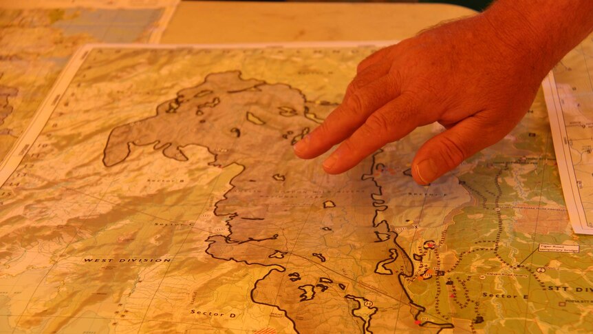 A firefighter points to the Gell River fire on a map