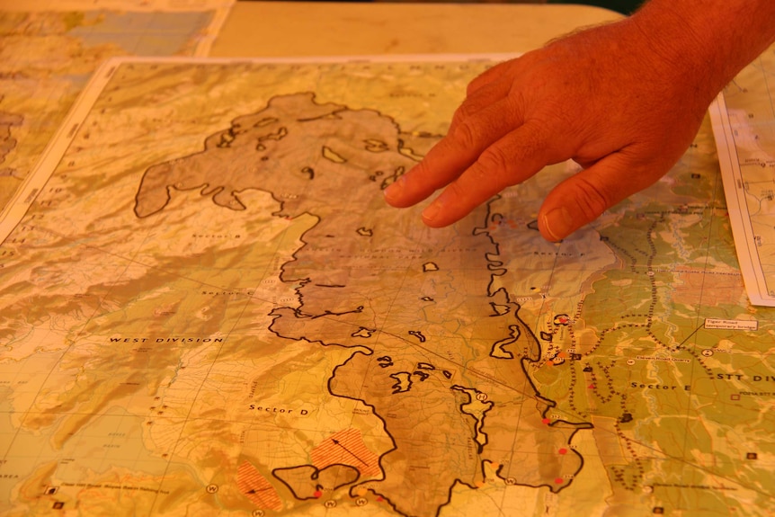 A firefighter points to the Gell River fire on a map