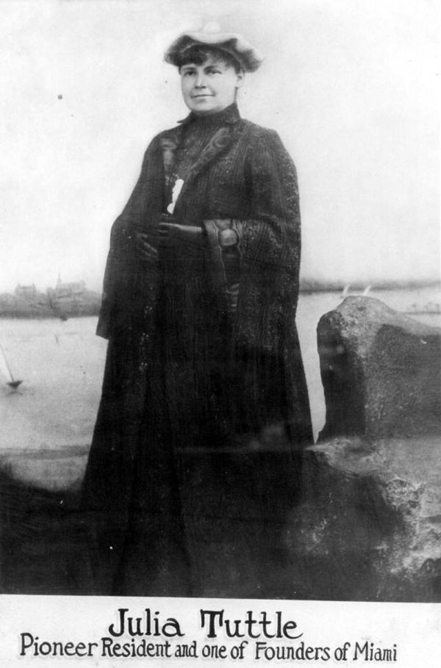 A woman wearing a bonnet and a black coat is pictured in a black and white vintage photograph.