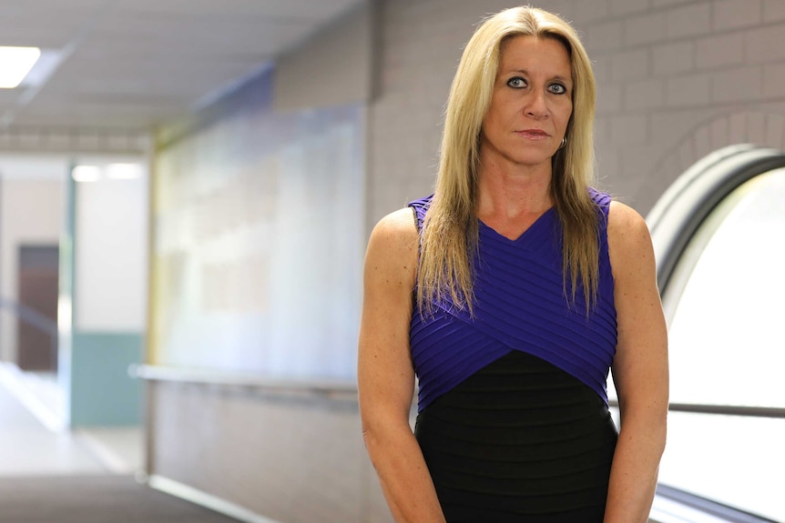 A woman stands in a hallway of a school.