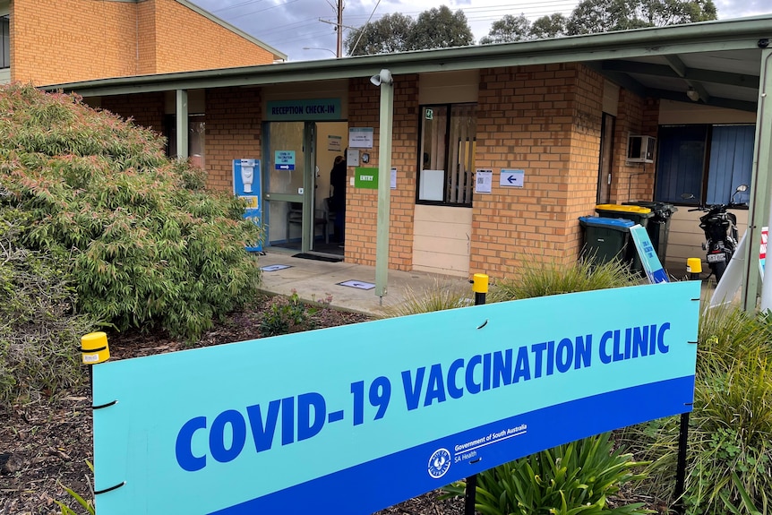 A covid vaccination clinic sign outside a brown brick building