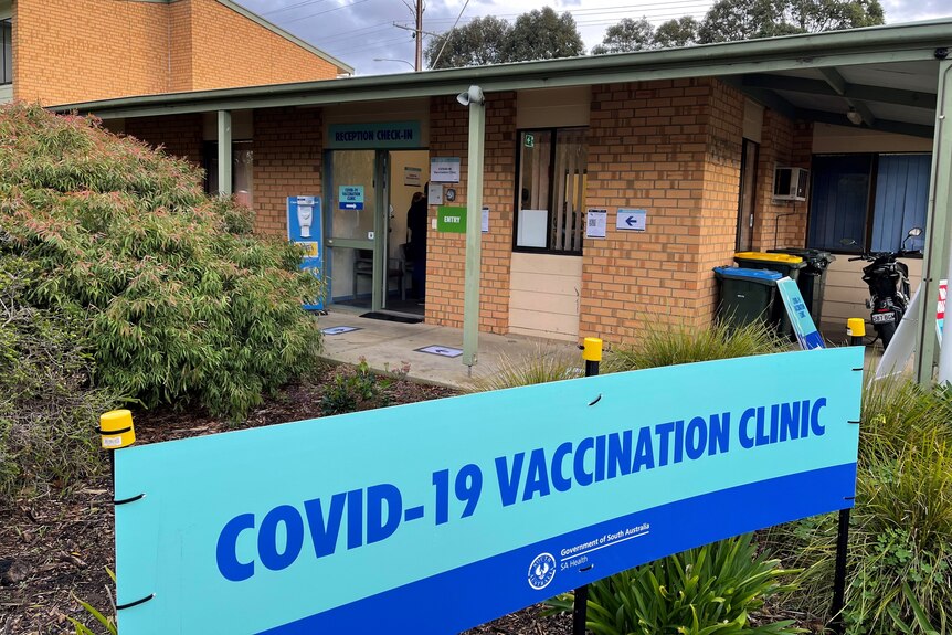 A covid vaccination clinic sign outside a brown brick building