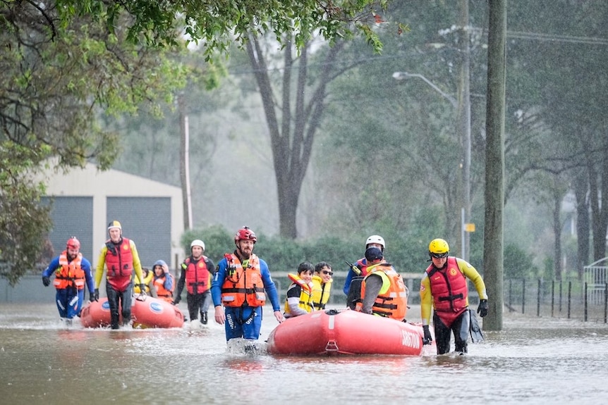 Lifesavers drag inflatable rescue boats through floodwater