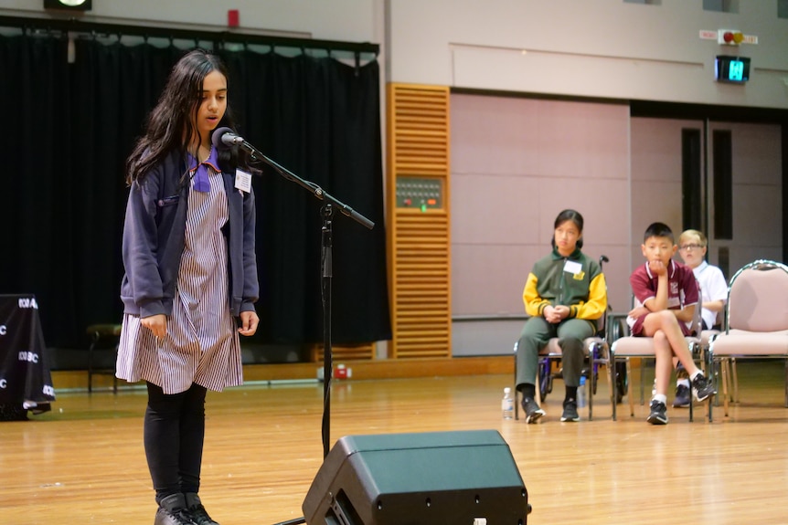 A girl speaks at a microphone