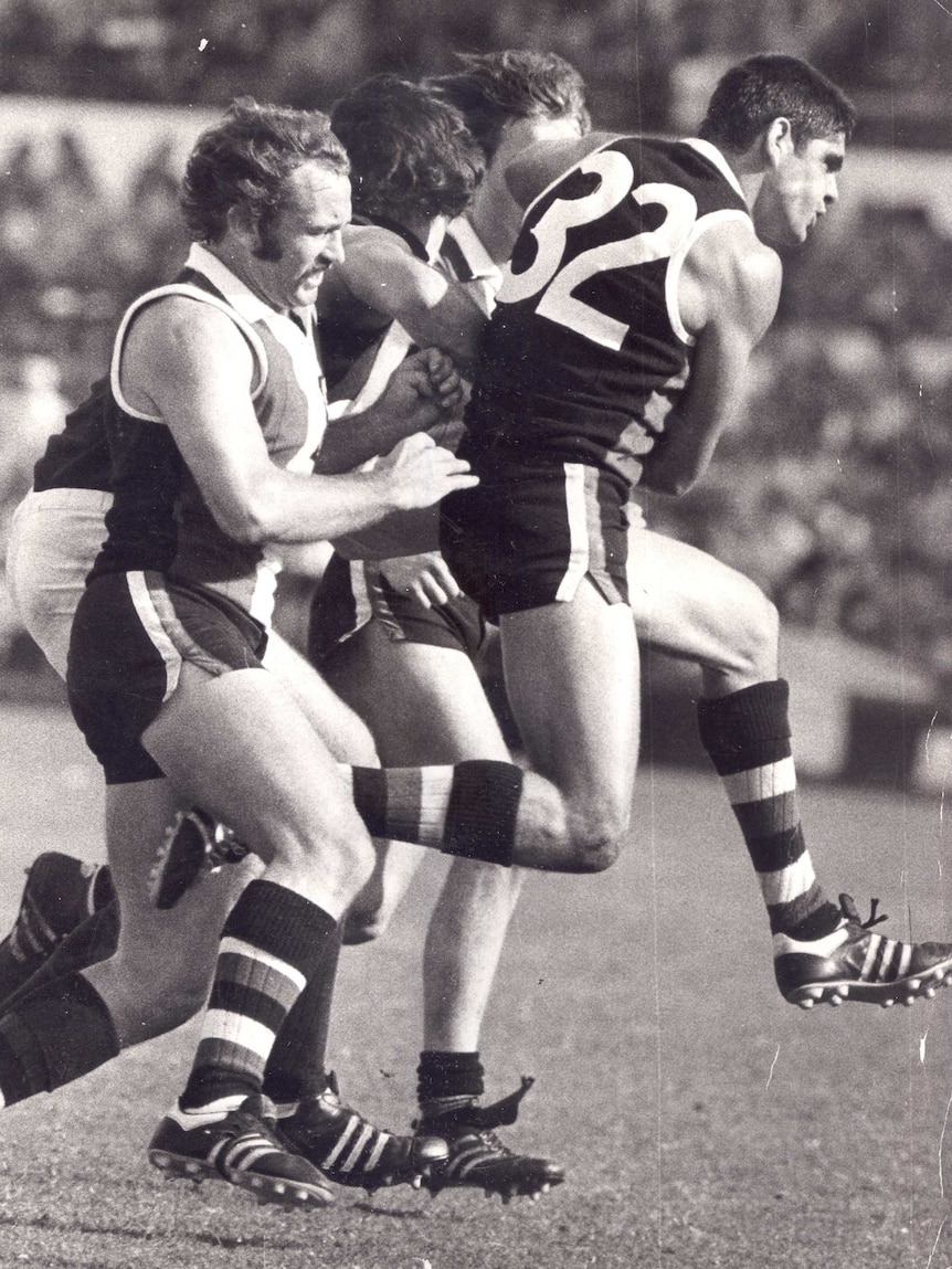 Four men jostle for the football in a VFL game.