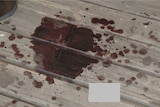 A dried splatter of blood on a sheet of tin. 