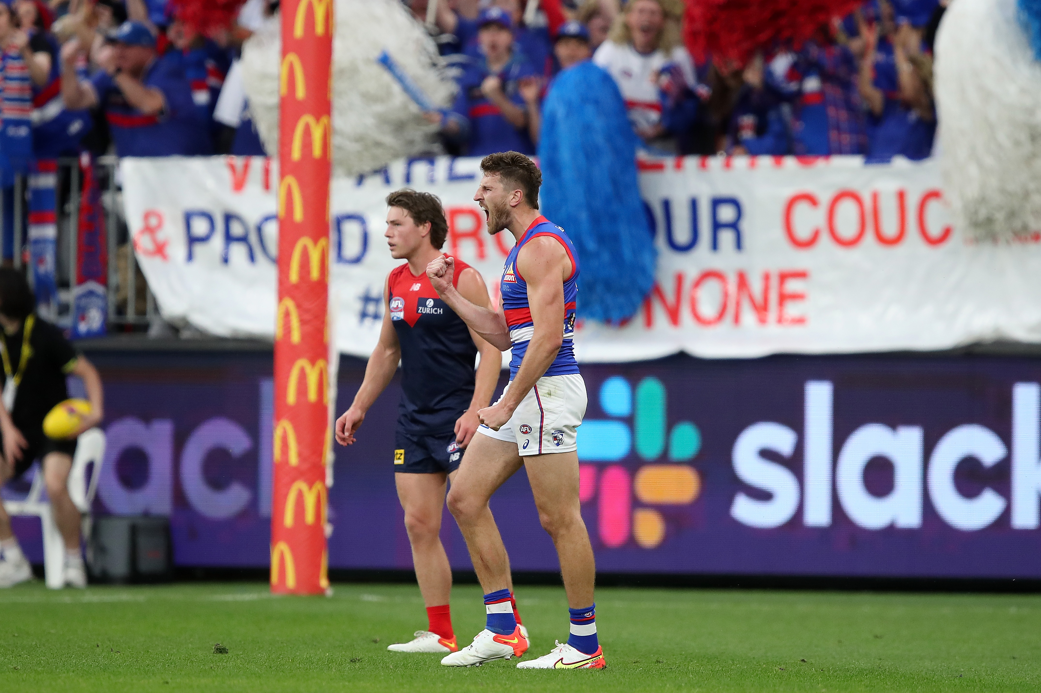 Marcus Bontempelli shouts and pumps his fist after and AFL grand final goal. A Melbourne Demon is in the background.