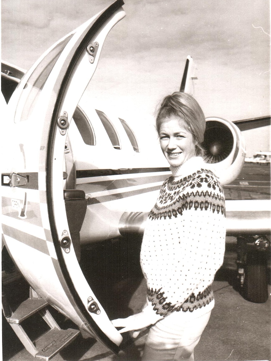 Robin Miller stands beside a plane.