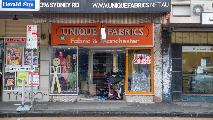 A homeless person's shelter is set up in the Unique Fabrics store front