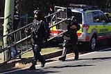 SERT officers make their way along a street near a unit complex at Currumbin on the Gold Coast.