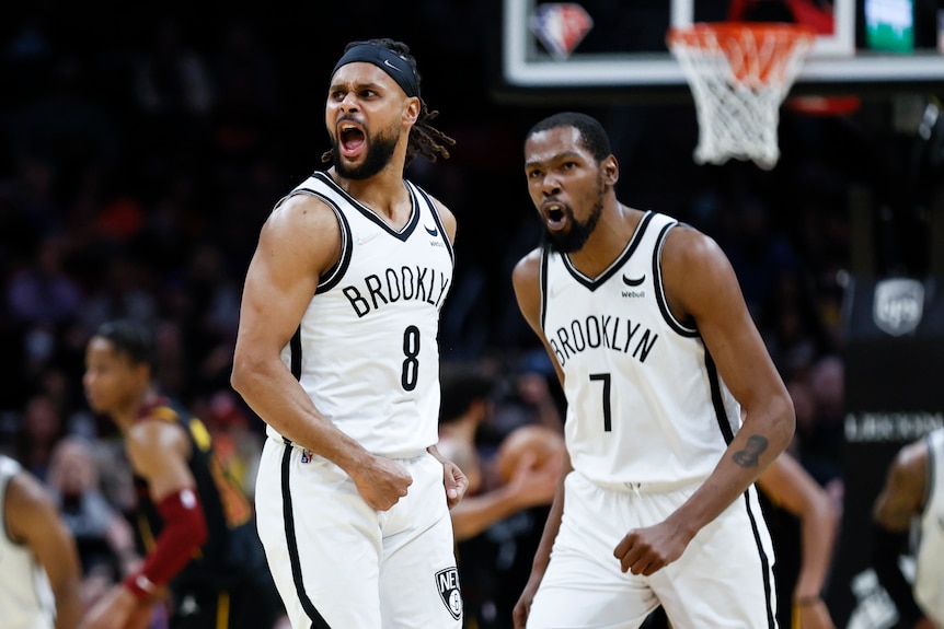 Brooklyn Nets players Patty Mills (left) and Kevin Durant shout in celebration during an NBA game.